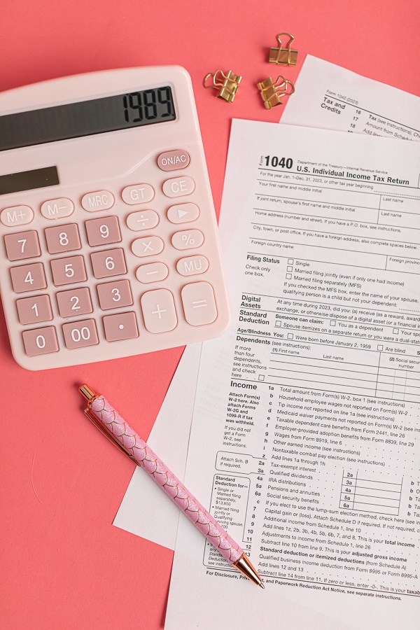 1040 income tax return and calculator on a pink background