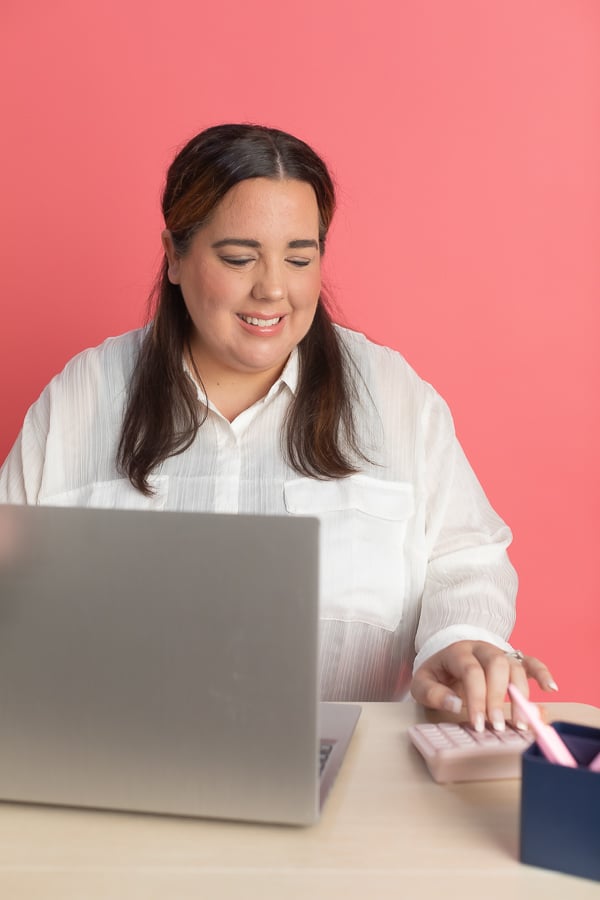 Accountant sitting at her desk using a laptop and a calculator